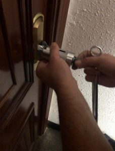 ¿Como abrir una puerta si te quedas las llaves puestas por dentro? 1 Manos de un cerrajero usando un extractor de bombín en una cerradura de puerta de seguridad